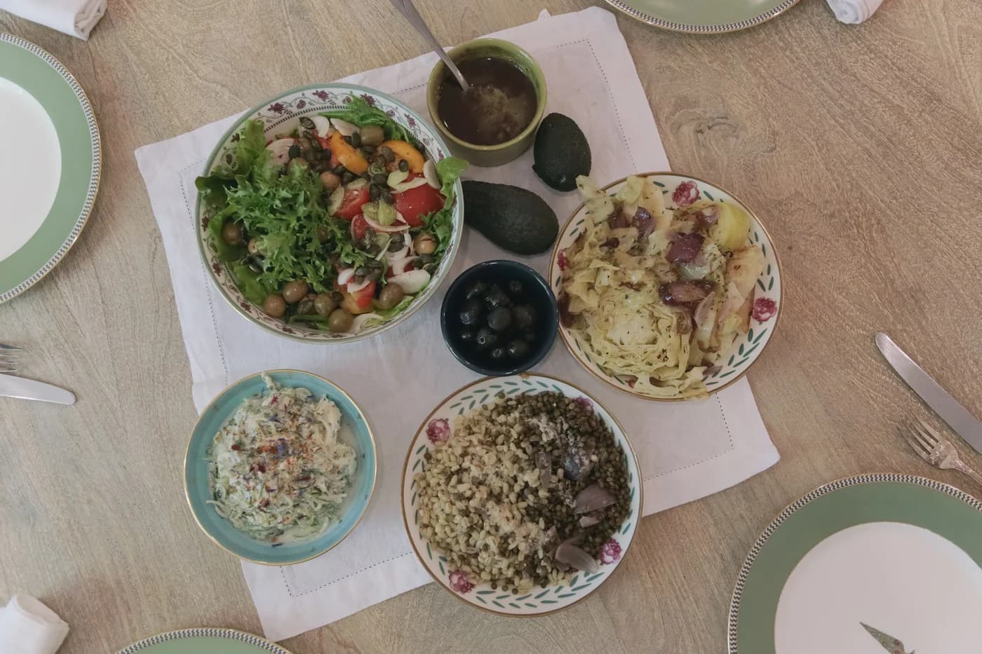 Table servie vue du dessus à Maison ilā : salade, lentilles, chou, olives, avocats. Photo : Joséphine