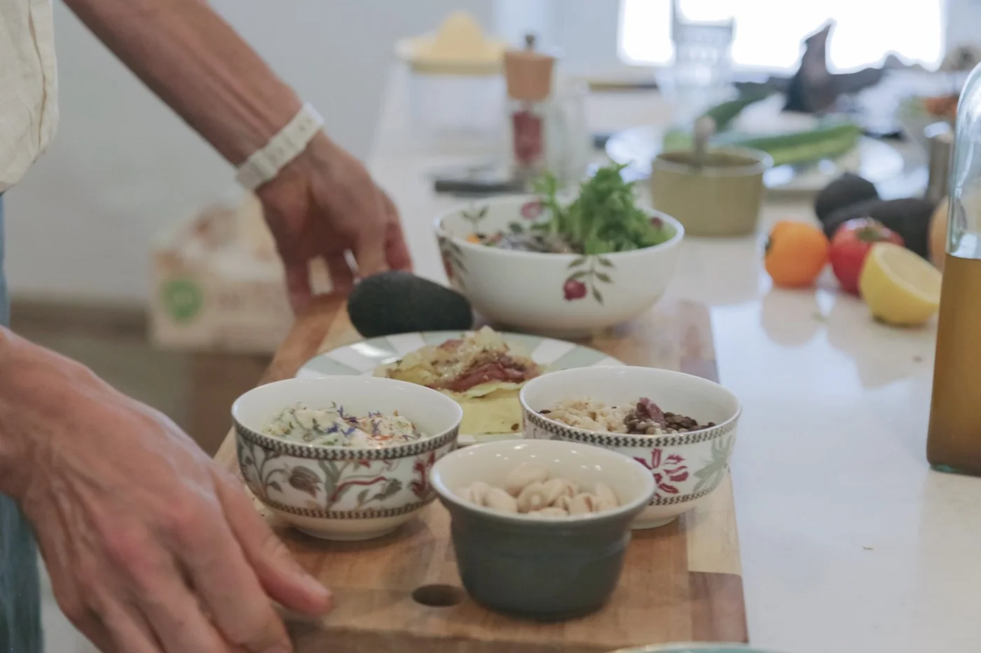 Les mains de Virgile posent des bols sur une planche, dans une cuisine claire