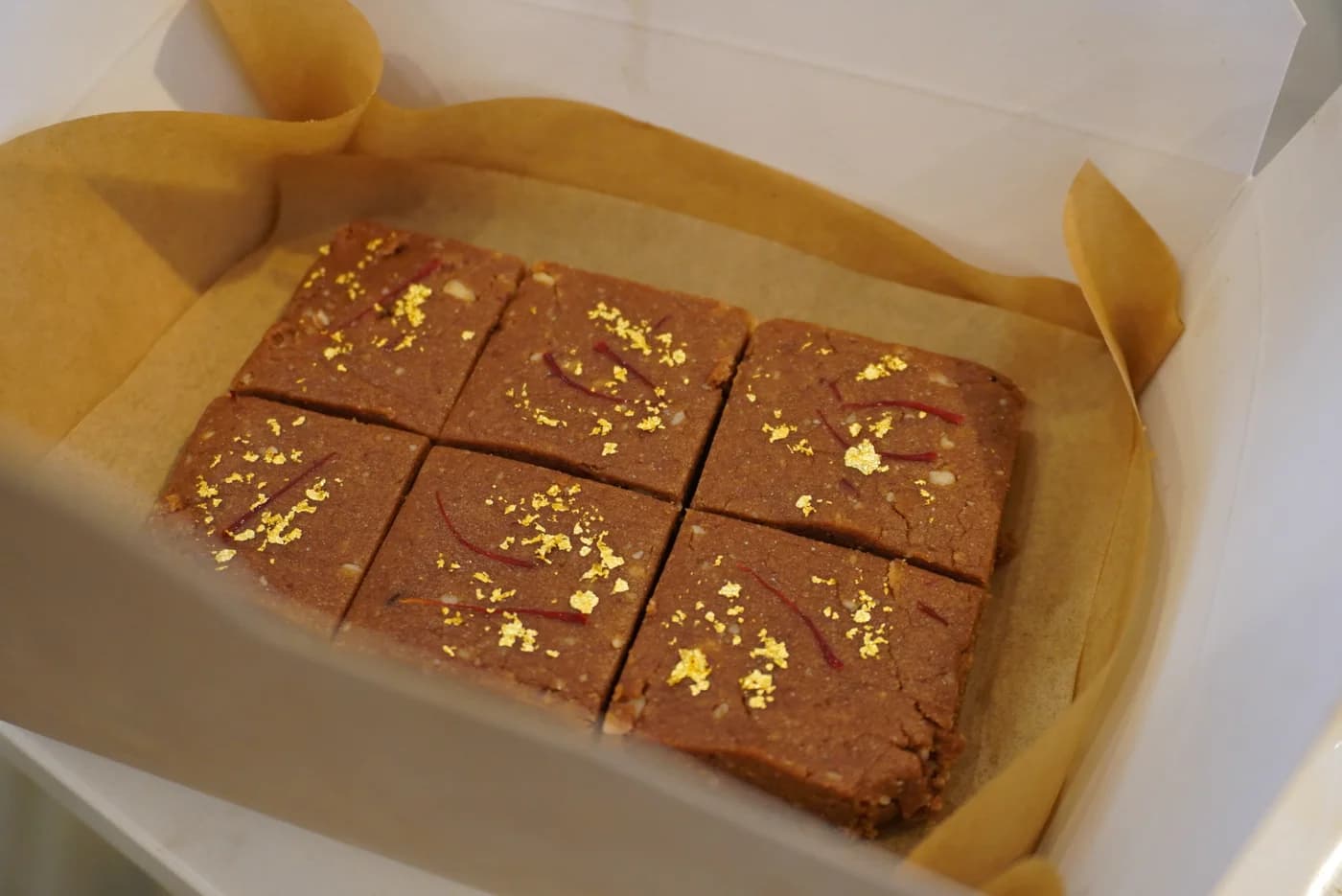 Carrés de chocolat cru à la feuille d'or, dans leur boîte